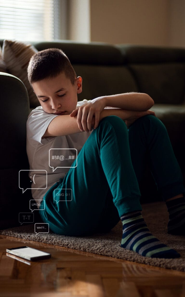 Boy sitting on floor at looking at smart phone feeling frustrated after reading bad message.